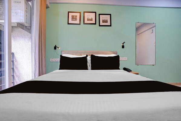A hotel room with a bed, a nightstand, a telephone, and three framed pictures on the wall.