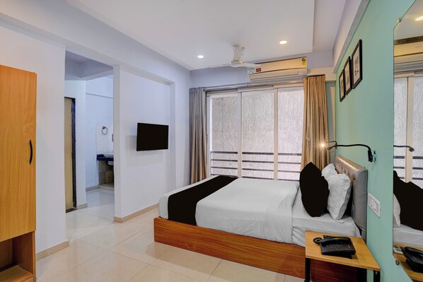 A hotel room with a bed, bedside table, and a TV mounted on the wall.