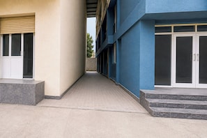 A building with a covered walkway, a set of steps leading to a door, and a tiled floor.
