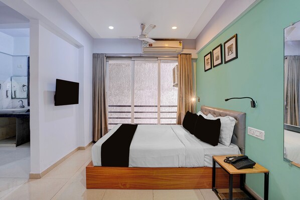 A modern bedroom with a bed, bedside table, and a television on the wall.