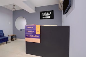 A reception desk with a sign indicating check-in at 12 pm and check-out at 11 am, and a no-smoking policy.