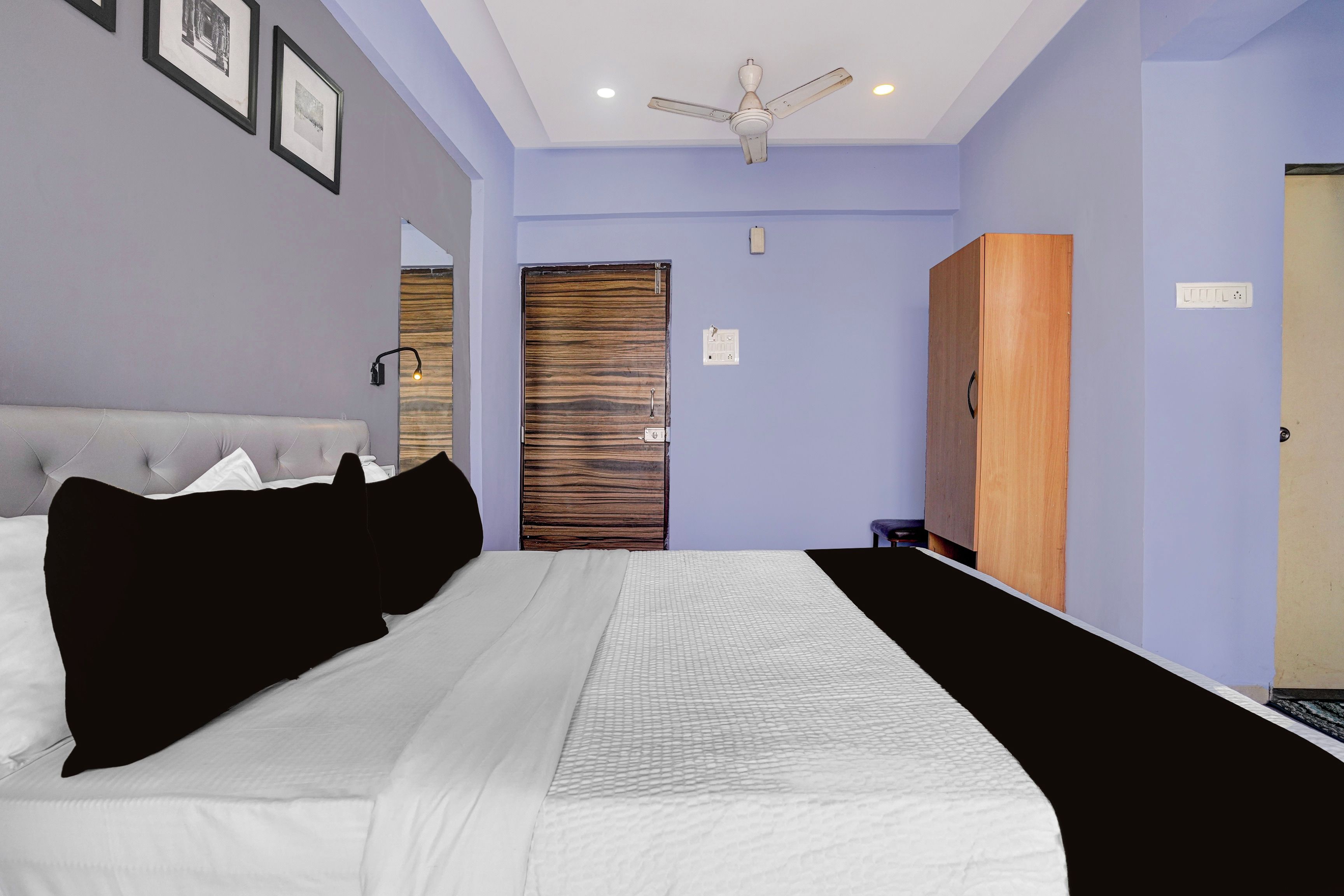 Un dormitorio con una cama, un armario, un ventilador de techo y una puerta.