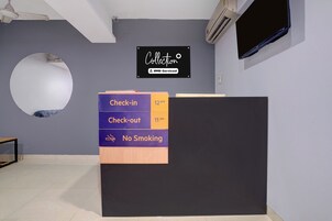 Una recepción con un cartel que indica hora de entrada a las 12:00 y hora de salida a las 11:00, además de una política de no fumar.