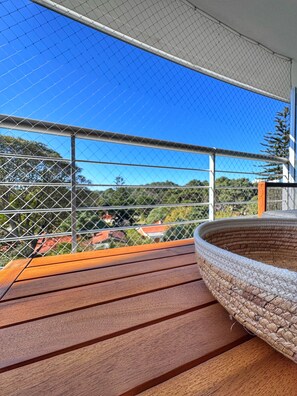 A wooden deck with a woven basket and a metal fence overlooking a residential area. - Spacious 2-Bedroom Apartment | Tressesenta Tower | Punta del Este (Punta del Este)