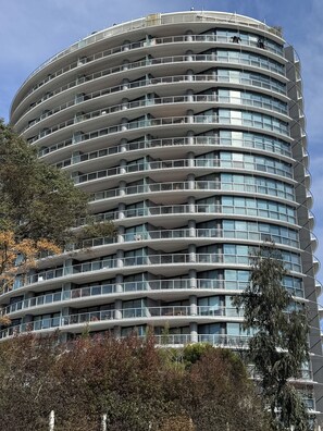 Un immeuble à plusieurs étages, doté d’une façade incurvée, de balcons et surplombant un ciel dégagé.