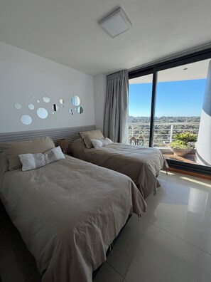 Une chambre d’hôtel moderne avec deux lits, une grande fenêtre et une vue sur la ville.