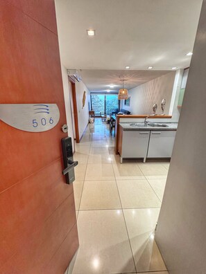 A modern hotel interior with a reception desk, a dining area, and a kitchen. - Spacious 2-Bedroom Apartment | Tressesenta Tower | Punta del Este (Punta del Este)