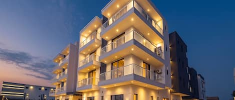 A multi-story residential building with balconies, a flat roof, and a well-lit facade.