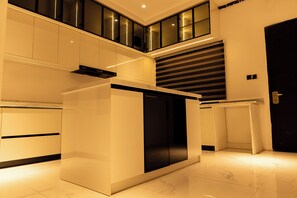 A modern kitchen with a sleek white and black color scheme, a built-in oven, and a large window above the counter. - Lefkosa Apartment (Jahi)