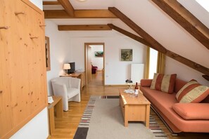 A cozy living room with a wooden ceiling, a sofa, a coffee table, and a chair. - ART HOTEL KRISTAL (Bohinj)