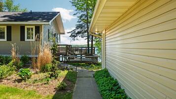 A residential property with a pathway leading to a wooden deck overlooking a body of water.