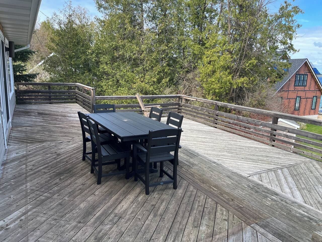 A wooden deck with a table and chairs, surrounded by a wooden railing.