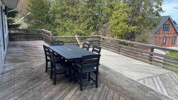 A wooden deck with a table and chairs, surrounded by a wooden railing.