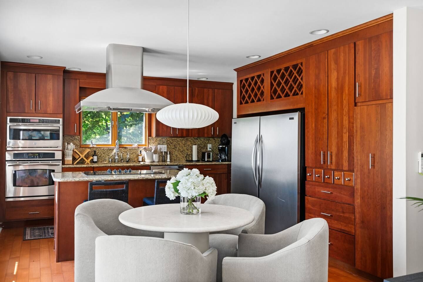 Una cocina moderna con electrodomésticos integrados, una isla central con asientos y un amplio ventanal que proporciona luz natural.