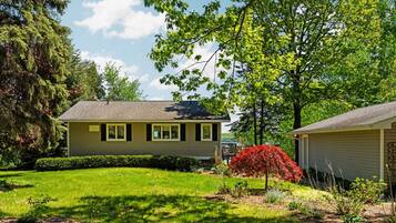 A two-story house with a well-maintained lawn and a variety of trees and shrubs.