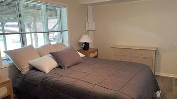 A bedroom with a bed, bedside table, lamp, and a dresser.