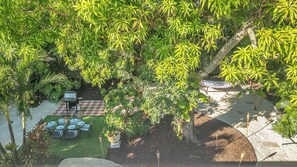 A patio area with a checkered table and chairs, surrounded by lush greenery and trees. - 5 bedroom/ 3 Bathroom Tropical Resort w/Gym near Pompano Beach and Parks (Pompano Beach)
