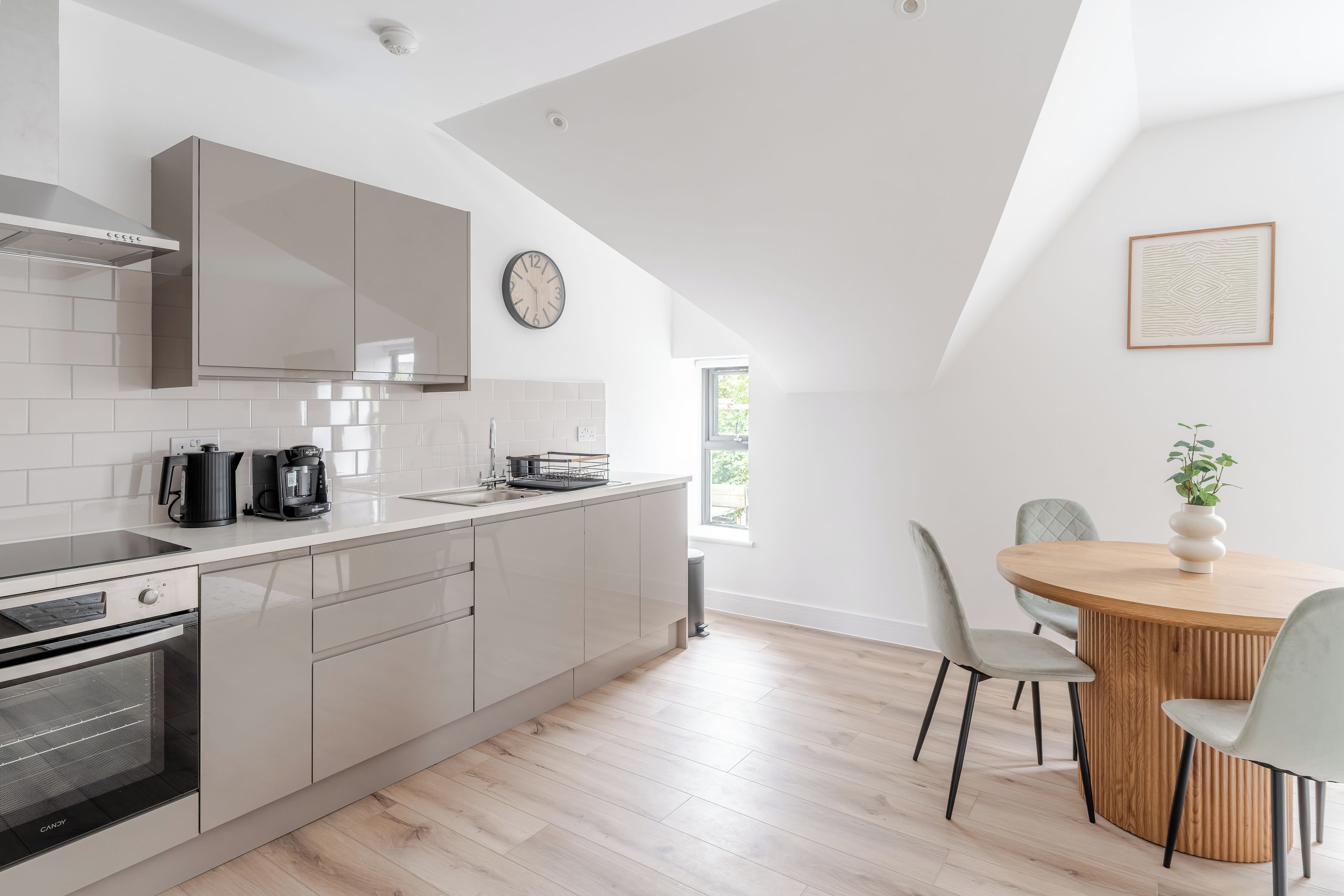 A modern kitchen with a built-in oven, a coffee maker, and a sink.