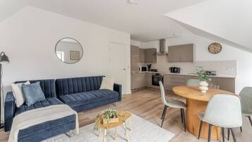 A modern apartment with a living room, dining area, and kitchen.