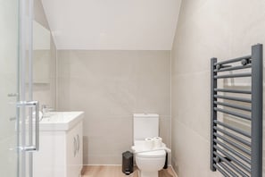 Un baño con inodoro, lavamanos y un perchero para toallas.