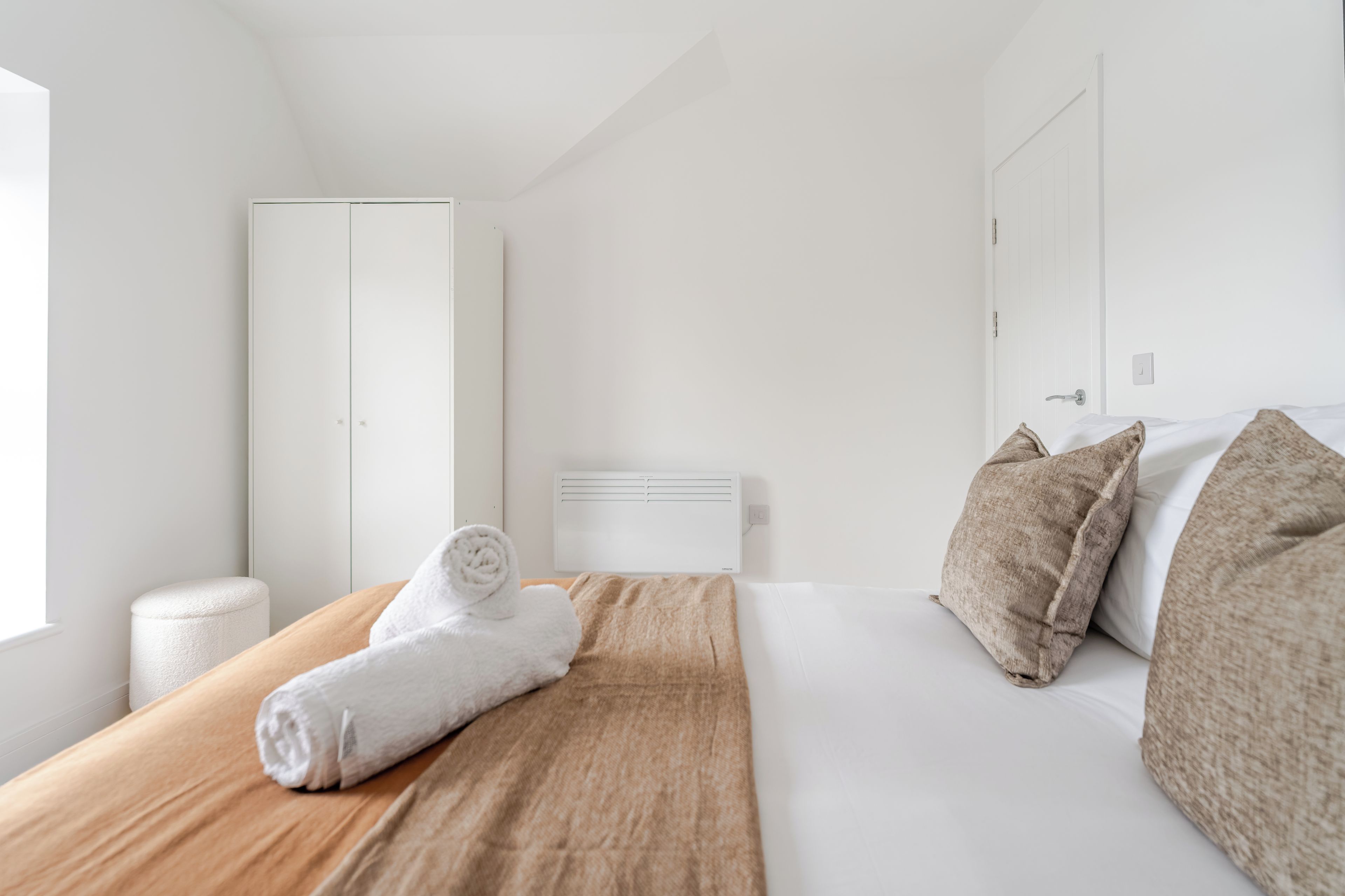 Et hotelværelse med en seng, et træpanel bag hovedgærdet, et hvidt skab og et vindue.