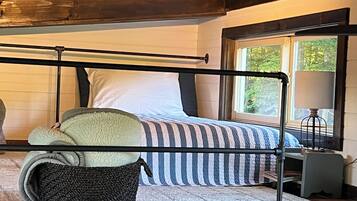 Ein Schlafzimmer mit Bett, Fenster, Lampe und Korb.