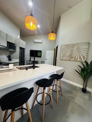 A modern kitchen with a central island, bar stools, and pendant lighting. - Premium 1-bedroom apartment in fantastic Pinilla-Tamarindo with AC-RANCHO-POOL (Provincia de Guanacaste)
