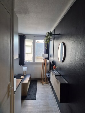 A modern kitchen with a window, a plant, a mirror, and a wooden stool. - Vrbo Property (Saint-Nazaire)