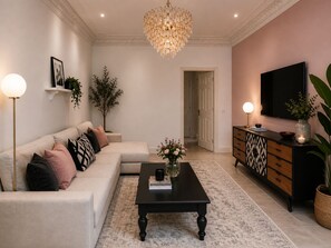 A living room with a sofa, coffee table, television, and decorative plants. - Stylish Hyde Park Residence with Portable AC (London)