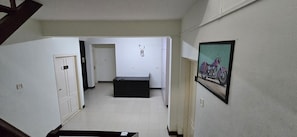 A hallway with a door labeled '103,' a black bench, and a framed picture on the wall.