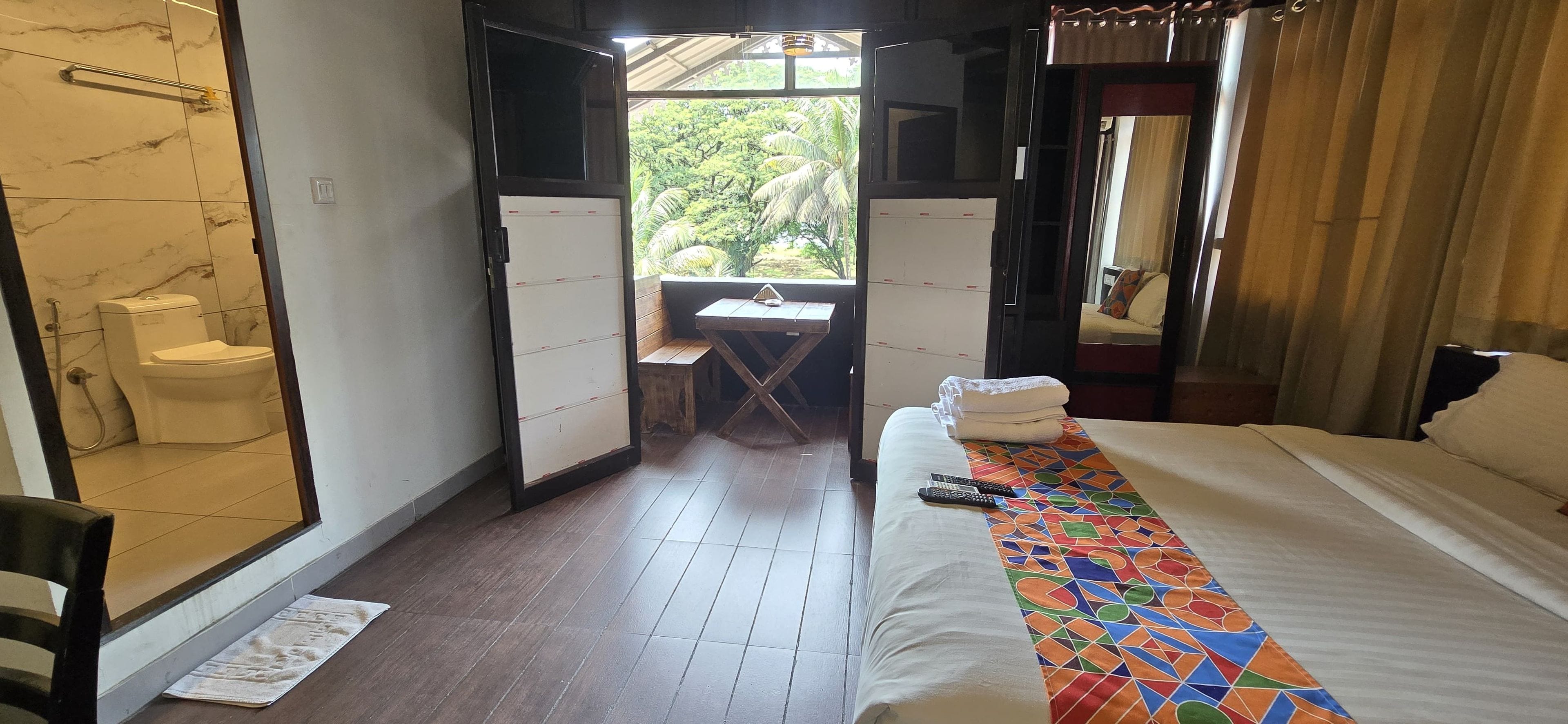 Ein Hotelzimmer mit einem Bett, einem kleinen Tisch, einer Bank und Blick auf Grünflächen.