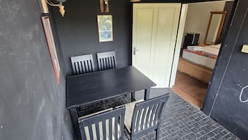 A room with a black table and chairs, a white door, and a bed with a colorful mattress.