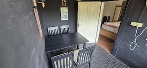 Una habitación con una mesa y sillas negras, una puerta blanca y una cama con colchón colorido.