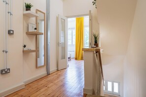 Un corridoio con pavimento in legno, una porta bianca e una tenda giallo brillante.