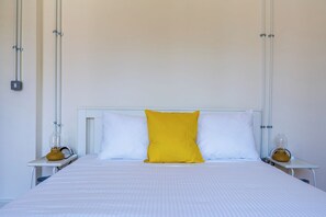 A bed with white bedding and a single yellow pillow, flanked by two bedside tables with lamps. - Casa Tomazo Spacious 2BRModern Heritage Old Town (Nicosia)