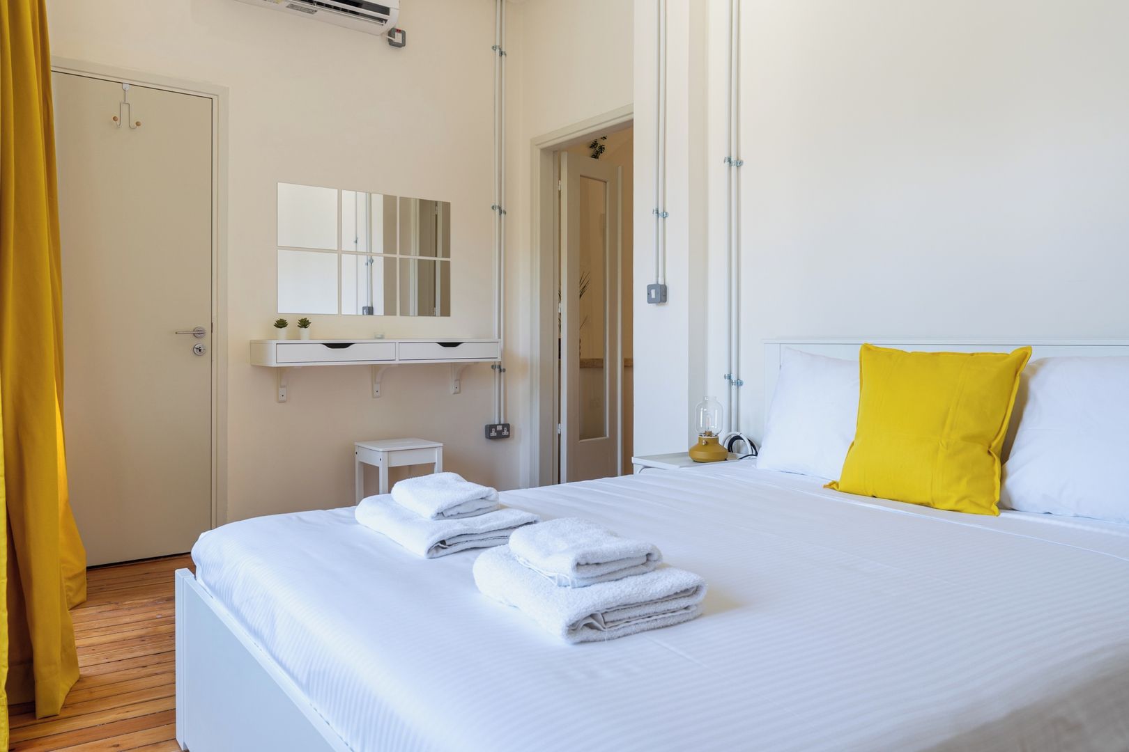Una camera d'albergo con un letto, un comodino, uno specchio e una finestra.