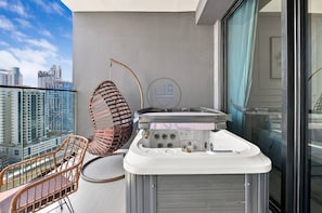 Ein Balkon mit Whirlpool, einem Korbstuhl und Blick auf die Stadt.