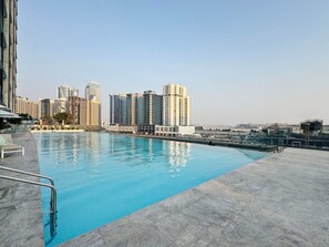 Ein Pool auf dem Dach mit Blick auf die Stadt, umgeben von Hochhäusern.