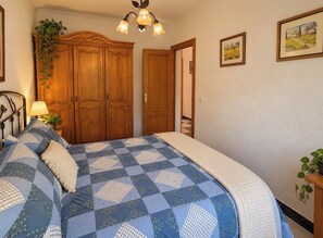Ein Schlafzimmer mit einem großen Bett, einem Holzschrank, einer Chandelier und einer Tür zu einem anderen Raum.