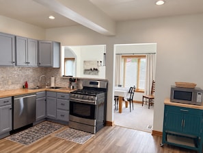 A modern kitchen with grey cabinets, a stainless steel stove, and a microwave.