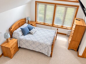 A bedroom with a bed, bedside tables, a dresser, a window with blinds, and a ceiling fan.