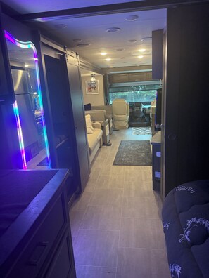 A compact RV interior with a kitchenette, seating area, and a small window. - Skip the ordinary hotel—stay somewhere unforgettable. (Leesburg)