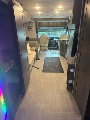 Interior de una caravana con zona de cocina, asientos y vistas por las ventanas.