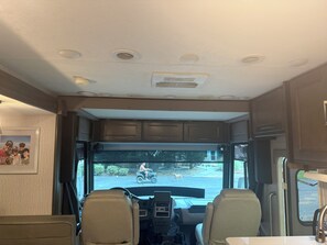 The interior of a recreational vehicle with a kitchen area, seating, and a view of the outside. - Skip the ordinary hotel—stay somewhere unforgettable. (Leesburg)