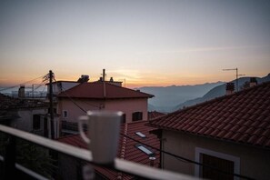A residential area with red-tiled roofs and a view of distant mountains during sunset. - Kokkovos Guesthouse Arachova by ΜΡS (Arachova)