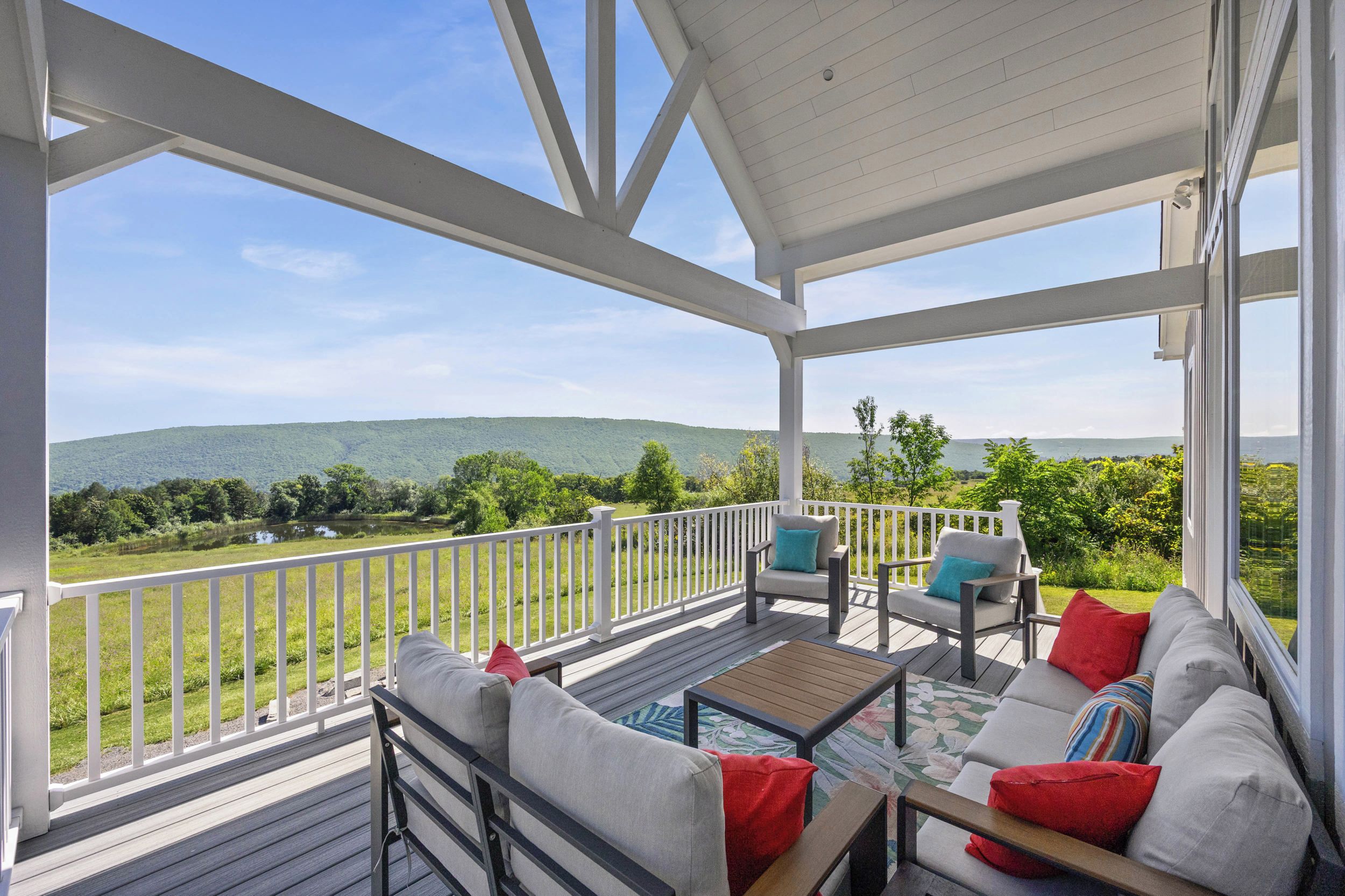 Une terrasse extérieure couverte avec vue sur un lac et des collines.