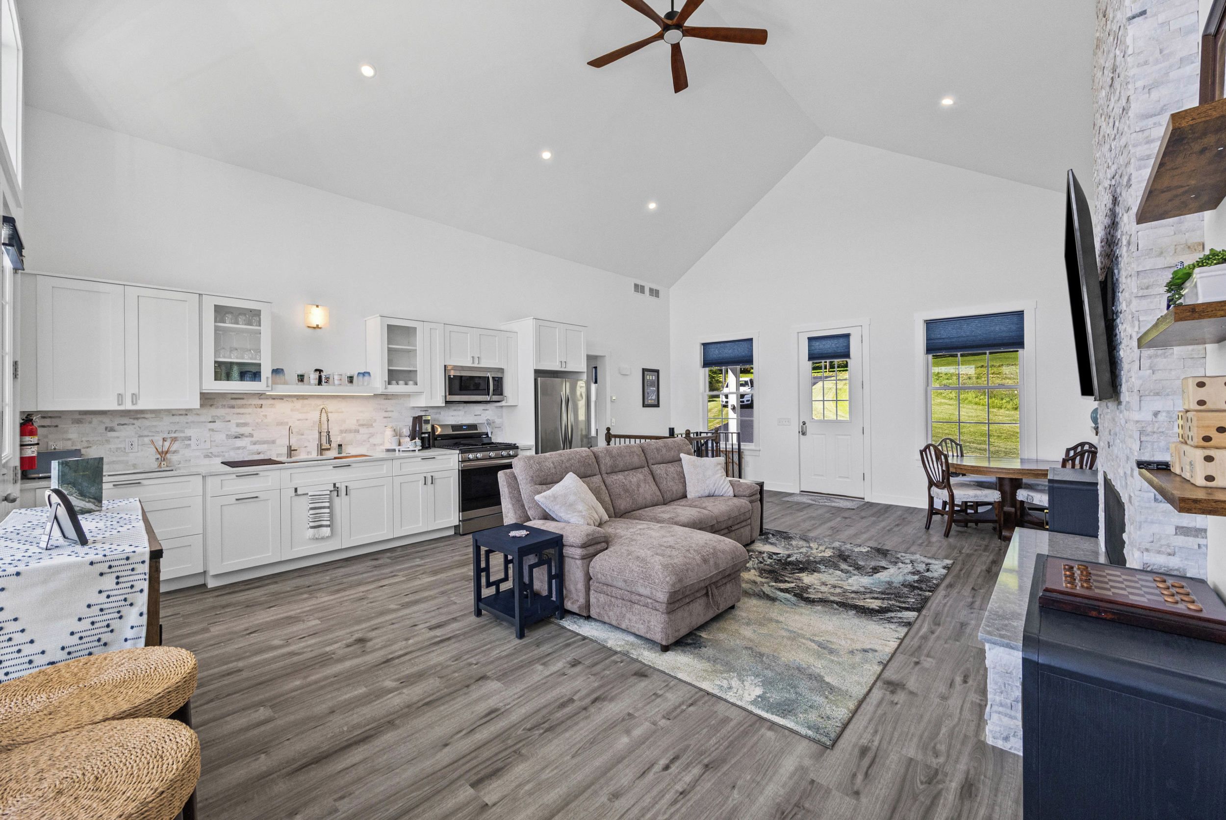 A spacious living area with a modern kitchen, a dining area, and a large window.