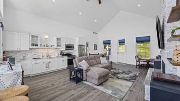A spacious living area with a modern kitchen, a dining area, and a large window.