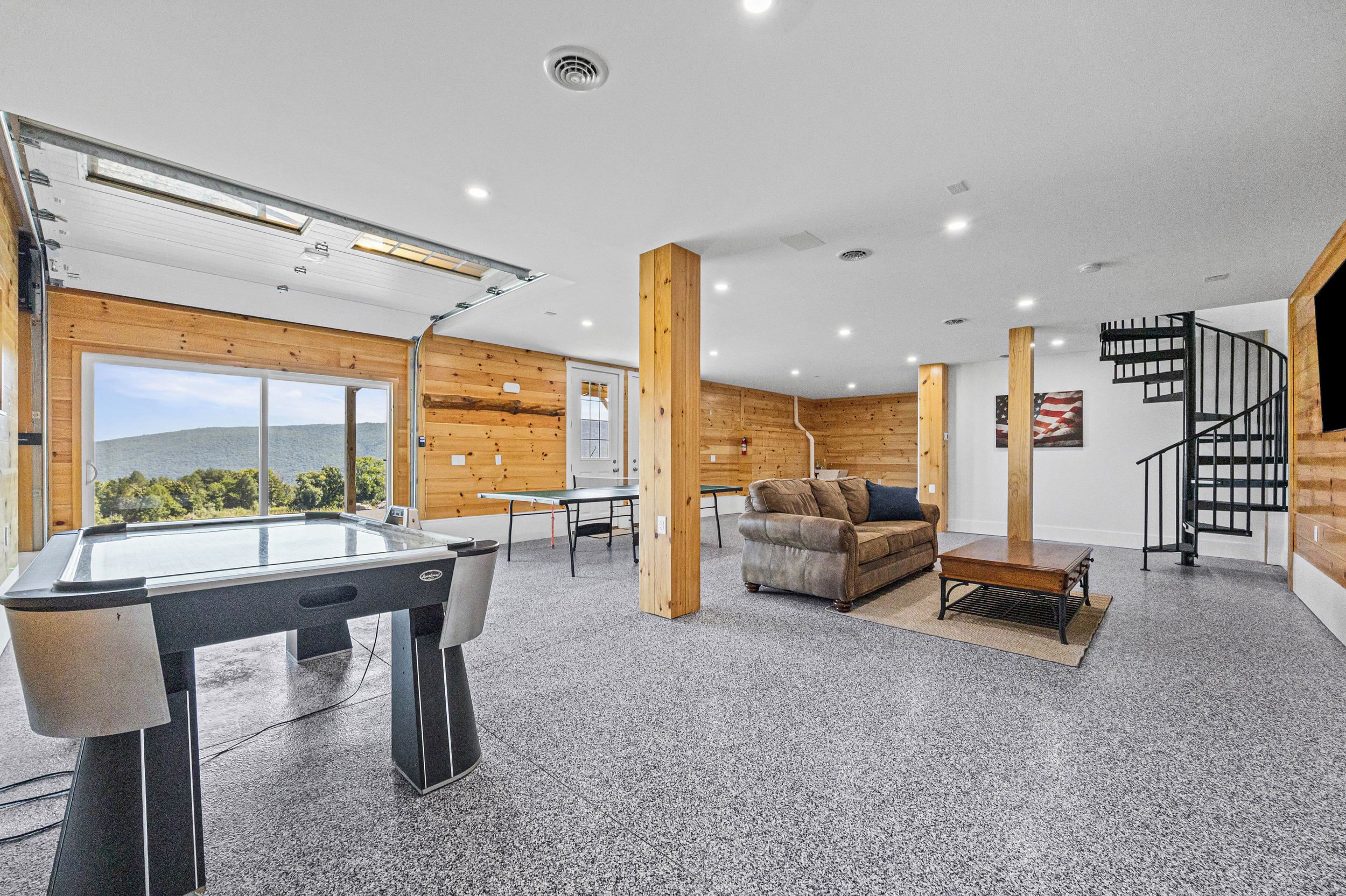 A modern interior with a pool table, a sofa, and a staircase.