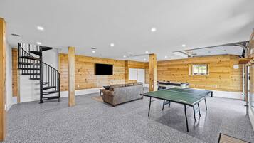 Una habitación con mesa de ping pong, un sofá y una escalera.